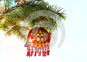 Christmas tree fir branch with hanging handmade craft new year toy ball pattern from red beads