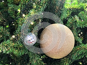 Christmas Tree fir close up decoration with glitter golden ball and mirror ball has blur bokeh light background selective focus.