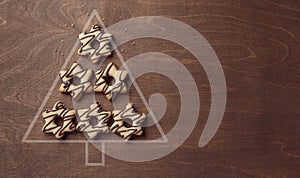 Christmas tree form made from star-shaped cookies with chocolate, banner on brown wooden background