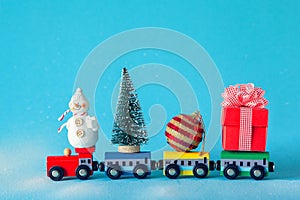 Christmas tree and gift box, ball and snowman on toy train on blue background. Gifts and congratulations concept