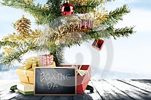 Christmas tree with gift box and Boxing Day text on the blackboard on wooden floor