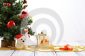 Christmas tree, gold gift box, balls, toy bear, candies and decorations on retro vintage white table isolated