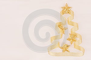 Christmas tree of gold stars, curl ribbons on soft white wood background.