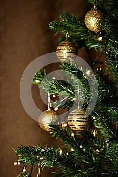 Christmas tree with golden balls and a luminous garland, with focus in the foreground and a blurred backdrop