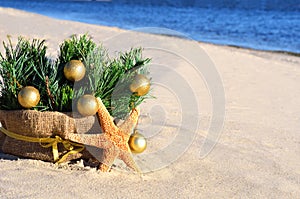 Christmas tree with golden christmas balls and starfish on the s