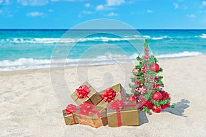 Christmas tree and golden gift with big red bow on the sea beach