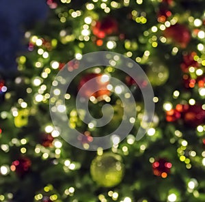 Christmas tree with golden and red decorations and lights, blurred abstract holiday background