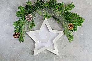 Christmas tree green branches with star photo frame on gray background. New year