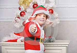 Christmas tree ideas for kids. Boy kid dressed as cute elf magical creature white artificial ears and red hat near