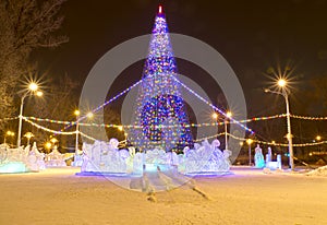 Christmas tree with illumination and ice town in the park. Night. Russia.