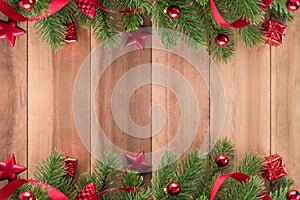 Christmas tree leaves with red ornaments on wood background