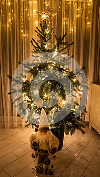 Christmas Tree with lights and Santa Claus figure in a low-light room