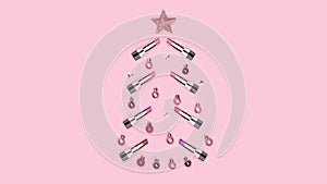 Christmas tree made of colorful lipsticks, Christmas balls, stars on pink background. Xmas concept. Makeup. Cosmetic.