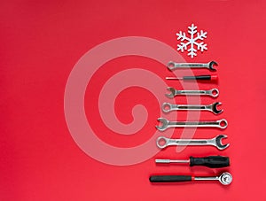 Christmas tree made of construction tools with a snowflake on a red background. New Year`s concept for a car workshop