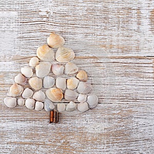 Christmas tree made from different type of sea shells and starfish with on wooden background. Sea shells shaped as a Christmas tre