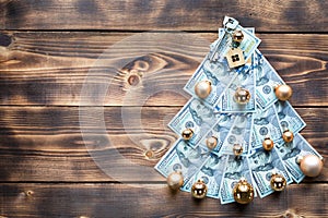 Christmas tree made of 100 dollar bills on wooden background with copyspace and House key. Christmas decor of finance, savings,