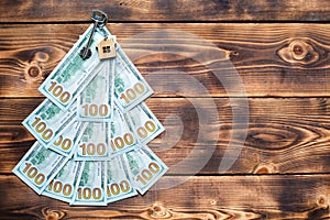 Christmas tree made of 100 dollar bills on wooden background with copyspace and House key. Christmas decor of finance, savings,