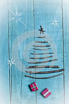 Christmas tree made from dry sticks on wooden, blue background. Snow flaks image. Christmas tree ornament, craft, gifts