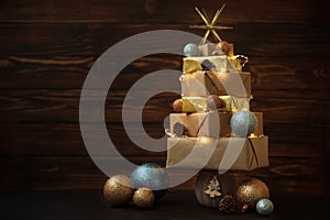 Christmas tree made from gift boxes with decorations against brown wooden background. Copy space.  Merry christmas and happy new