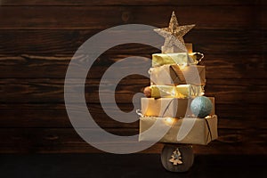 Christmas tree made from gift boxes with decorations against brown wooden background. Copy space.  Merry christmas and happy new