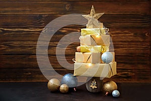 Christmas tree made from gift boxes with decorations against brown wooden background. Copy space.  Merry christmas and happy new