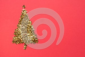 Christmas tree made of golden stars glitter confetti on red background. Xmas holiday backdrop