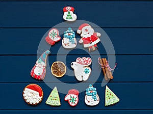 Christmas tree made with homemade gingerbread cookies on plate on classic blue wooden background. Snowflake, star, tree, snowman