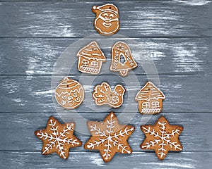 Christmas tree made with homemade gingerbread cookies on plate on gray wooden background. Snowflake, star, tree, snowman,