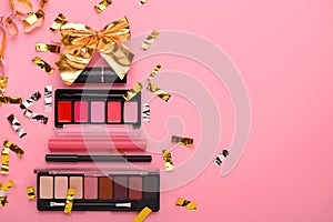 Christmas tree made from makeup products on a pink background top view. Cosmetic beauty products for Xmas,lipstick, shadows