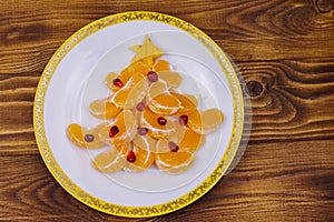 Christmas tree made of mandarin lobules and pomegranate on wooden table. Top view. Creative idea for Christmas and New Year