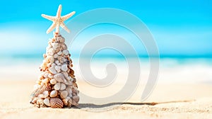 Christmas tree made of seashells and corals with a starfish on the top on blurred tropical beach background.