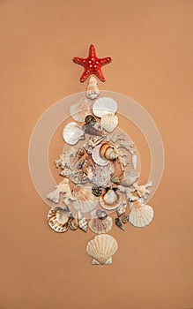 The Christmas tree is made of shells, coral twigs and a red starfish on a beige background.