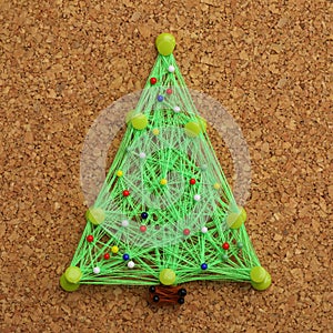 Christmas tree made of thread and pins on cork board
