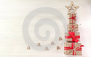 Christmas tree made from wrapped gift boxes with red ribbons with a star on a wooden background