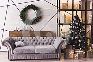 Christmas tree in modern white living room with coach, candles and wreath