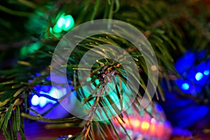 Christmas tree needles on a background of green, red and yellow LED lights. Nightly magic and fairy tale. Macro. Bokeh, volume and