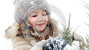 Christmas tree outdoor decoration. cutie, pretty little girl decorates snow-covered Christmas tree with homemade ice