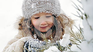 Christmas tree outdoor decoration. cutie, pretty little girl decorates snow-covered Christmas tree with homemade ice