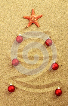 Christmas tree on painting in sand with red starfish and red matt christmas balls