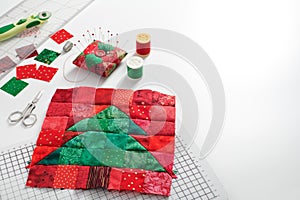 Christmas tree patchwork block, bright square pieces of fabric, pincushion, quilting and sewing accessories on white background