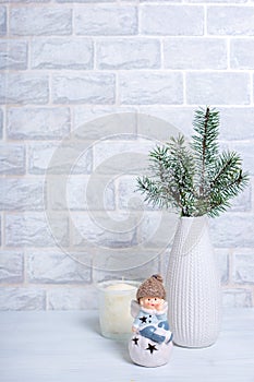 Christmas Tree Pine Branches in a vase, candle and Christmas toy on a light vertical background. New Year