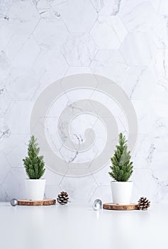 Christmas tree with pine cone,decor xmas ball on wood log at white table and marble tile wall background.clean minimal simple