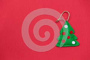 Christmas tree on red background. Handmade toy from felt. DIY concept. Copy space