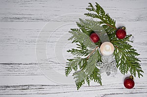 Christmas tree, red bauble balls and a candle on a light wooden background
