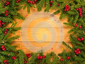 Christmas tree and red berries frame on the wooden background wi