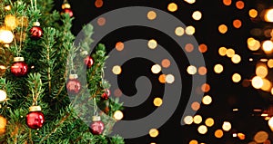 Christmas tree with red Christmas decorations on dark holiday background with bokeh, blurred, sparking