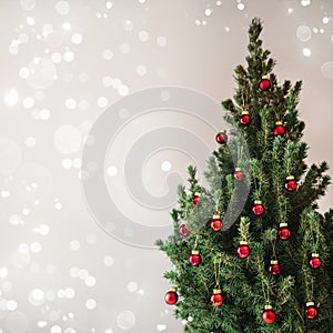 Christmas tree with red Christmas decorations on holiday background with snow, blurred, sparking