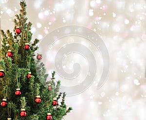 Christmas tree with red Christmas decorations on holiday background with snow, blurred, sparking