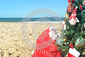 Christmas tree and red Santa bag of presents at the beach