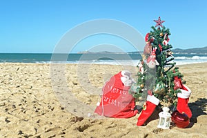 Christmas tree and red Santa bag of presents at the beach